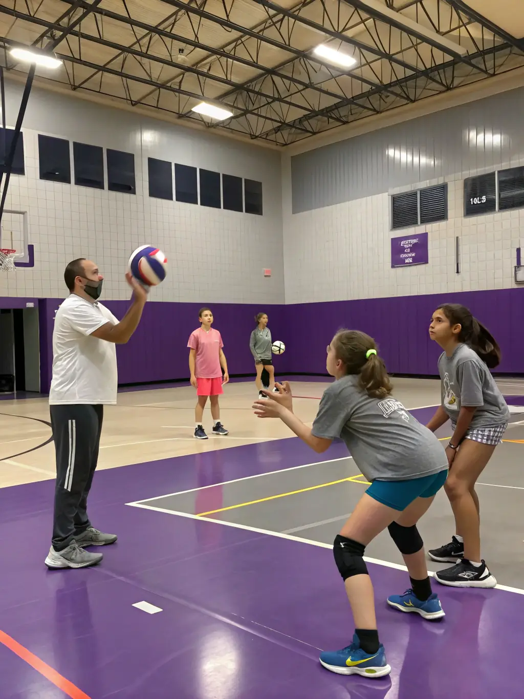 Action shot of young volleyball players participating in a training session, focusing on teamwork and skill development, set against the backdrop of a local sports hall.